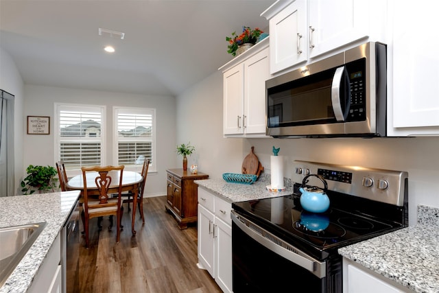 kitchen featuring light stone counters, stainless steel appliances, visible vents, white cabinets, and dark wood-style floors