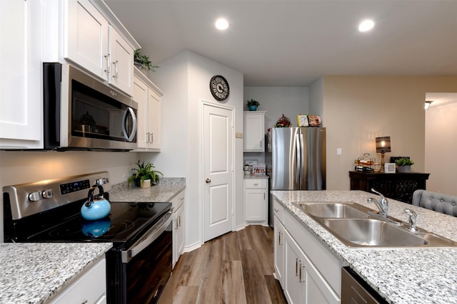 kitchen with white cabinetry, stainless steel appliances, a sink, and wood finished floors