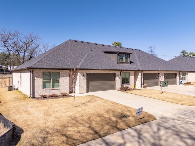 view of front of house with brick siding, a shingled roof, concrete driveway, a garage, and cooling unit