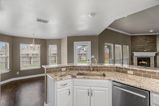 kitchen featuring visible vents, white cabinets, a sink, dishwasher, and a lit fireplace