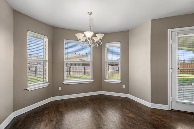 empty room featuring dark wood-style floors, baseboards, and an inviting chandelier