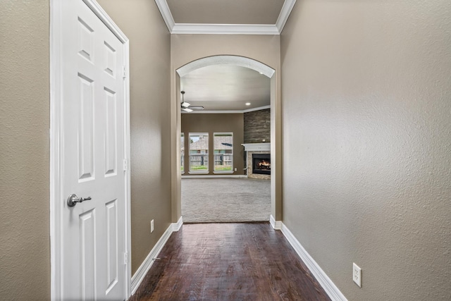 corridor featuring ornamental molding, arched walkways, dark wood-type flooring, and baseboards