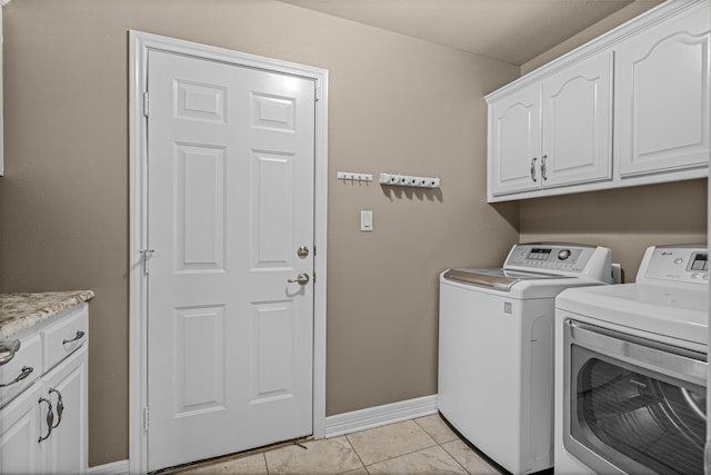 clothes washing area featuring cabinet space, light tile patterned floors, baseboards, and washing machine and clothes dryer