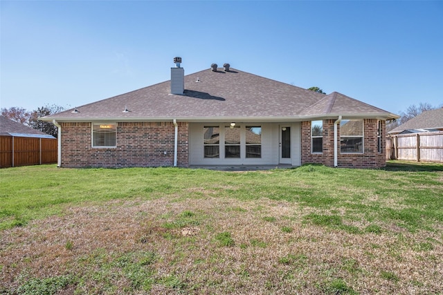 back of property with brick siding, fence, and a yard