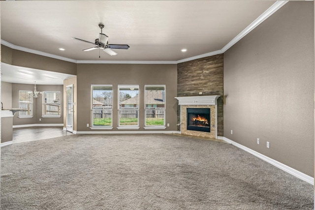 unfurnished living room featuring ornamental molding, a tile fireplace, carpet flooring, and ceiling fan with notable chandelier