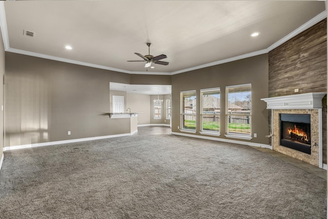 unfurnished living room featuring crown molding, visible vents, a tiled fireplace, a ceiling fan, and carpet flooring