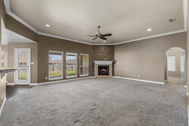 unfurnished living room with arched walkways, ceiling fan, a tiled fireplace, and baseboards