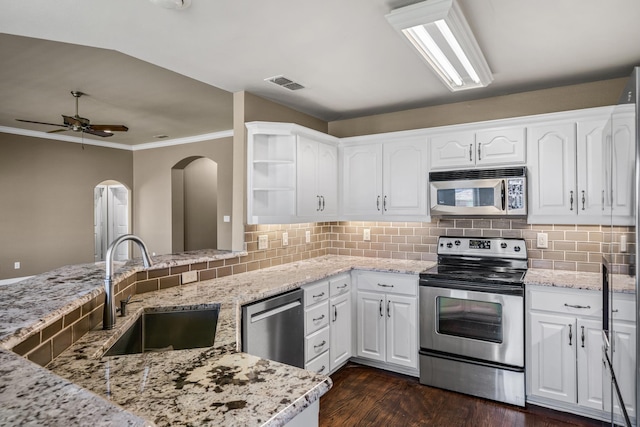 kitchen featuring stainless steel appliances, decorative backsplash, white cabinets, a sink, and light stone countertops