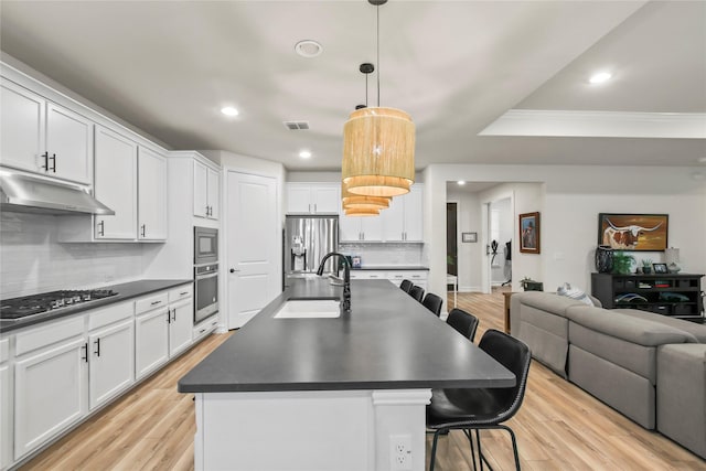 kitchen with stainless steel appliances, dark countertops, a sink, and under cabinet range hood