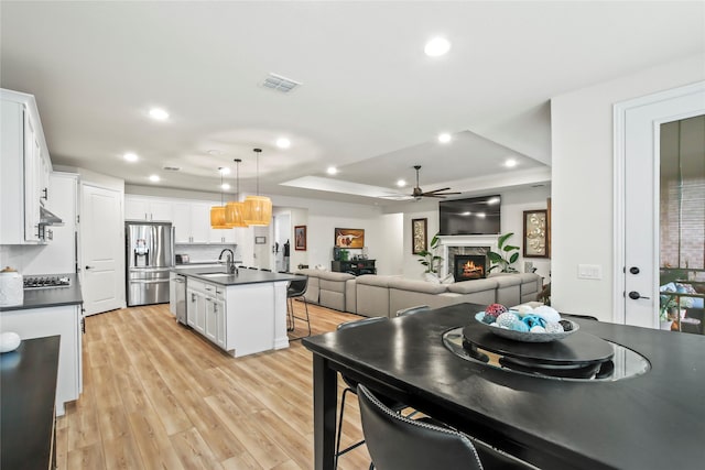 kitchen featuring a kitchen island with sink, white cabinetry, a kitchen breakfast bar, appliances with stainless steel finishes, and dark countertops