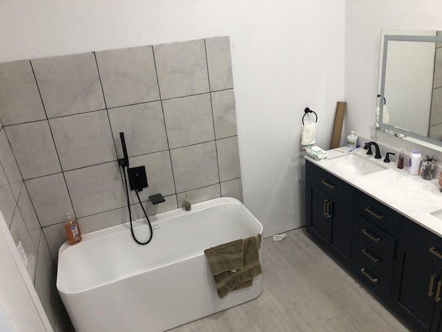 bathroom with double vanity, a freestanding tub, and a sink