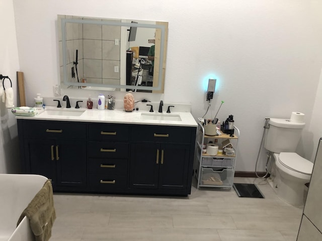 bathroom with a sink, toilet, and double vanity