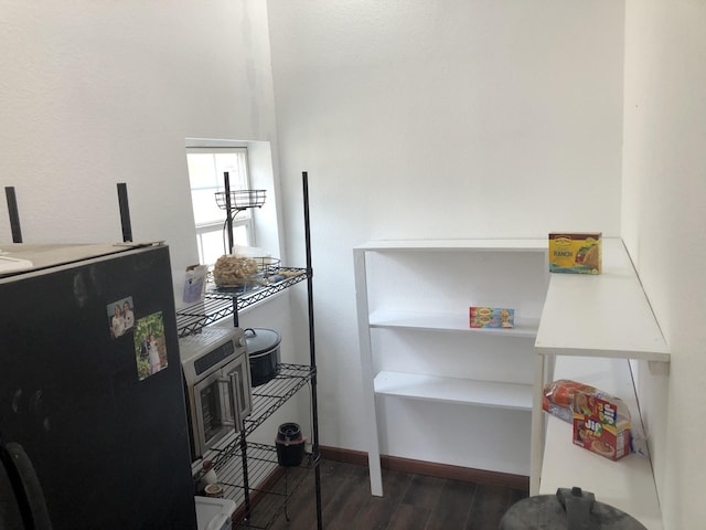 interior space featuring dark wood finished floors, freestanding refrigerator, and baseboards