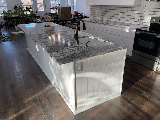 kitchen featuring electric stove, white cabinetry, a sink, and light stone countertops