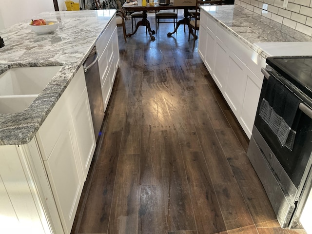 kitchen featuring light stone counters, dark wood-type flooring, white cabinetry, appliances with stainless steel finishes, and decorative backsplash