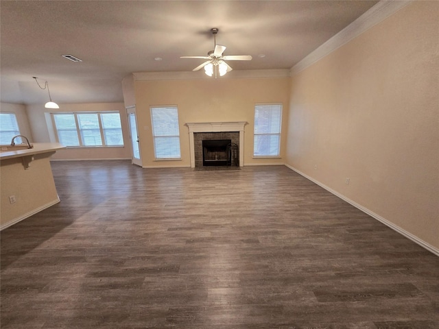 unfurnished living room featuring dark wood-type flooring, a fireplace, a sink, visible vents, and crown molding