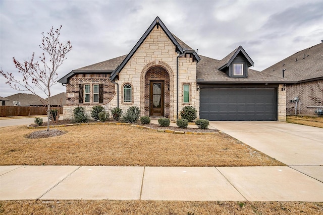 view of front facade with a garage, concrete driveway, a shingled roof, and stone siding