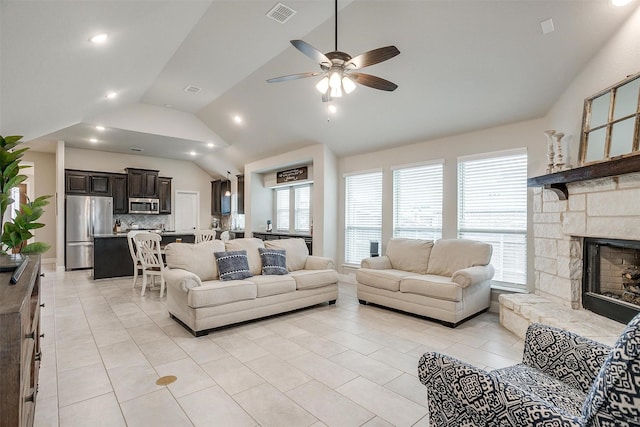 living area with high vaulted ceiling, visible vents, a stone fireplace, and light tile patterned floors