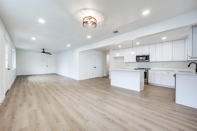 kitchen with appliances with stainless steel finishes, light countertops, open floor plan, and white cabinets