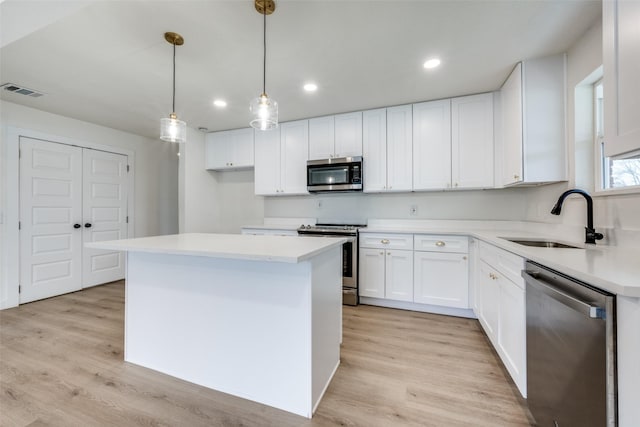 kitchen with a center island, light countertops, appliances with stainless steel finishes, white cabinets, and a sink