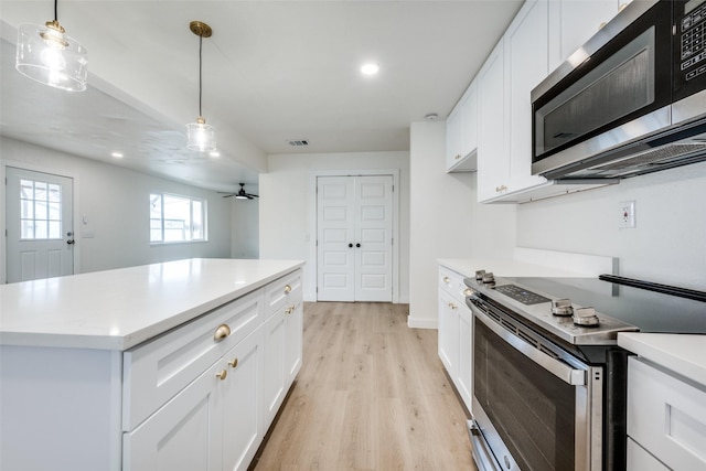 kitchen with decorative light fixtures, stainless steel appliances, light countertops, light wood-style floors, and white cabinetry