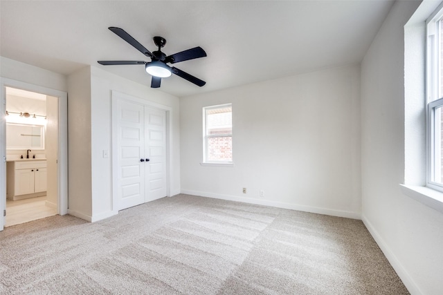 unfurnished bedroom with light carpet, a sink, and baseboards