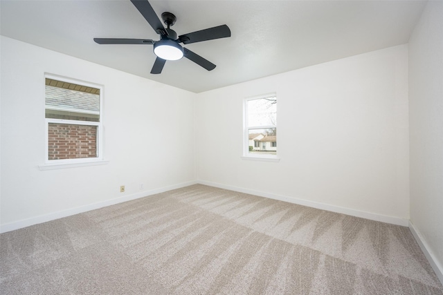 carpeted empty room featuring baseboards and a ceiling fan