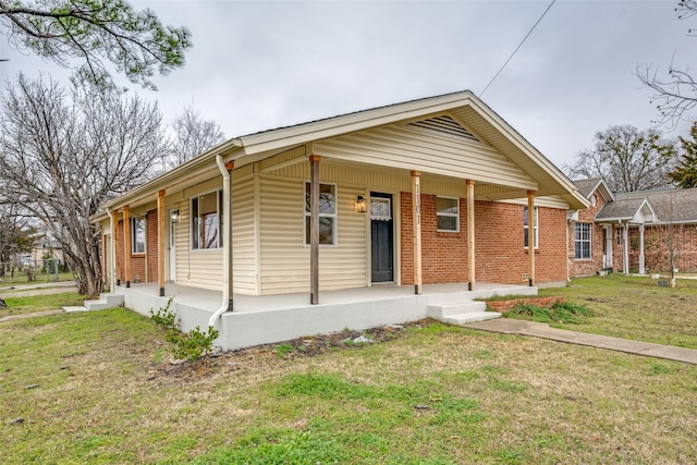 view of front facade featuring a front yard, covered porch, and brick siding