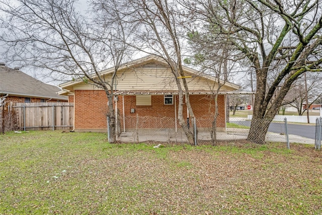 rear view of house with brick siding, fence, a patio, and a lawn