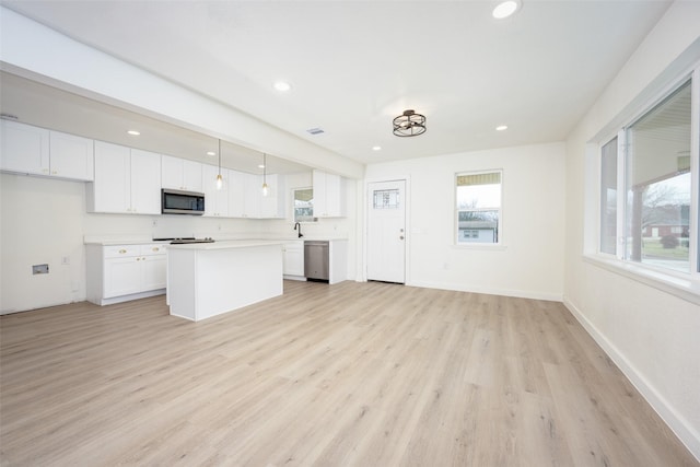 kitchen featuring light countertops, hanging light fixtures, appliances with stainless steel finishes, white cabinets, and a kitchen island