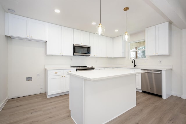 kitchen featuring light countertops, hanging light fixtures, appliances with stainless steel finishes, white cabinets, and a kitchen island