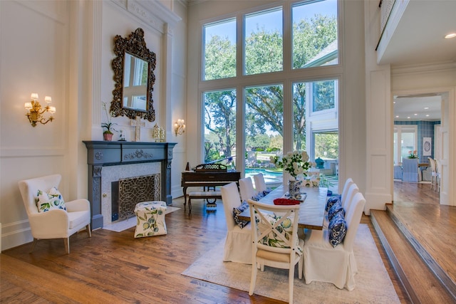 dining space with a fireplace with flush hearth, wood finished floors, and a towering ceiling