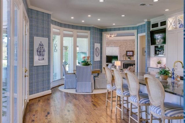 interior space with wood finished floors, crown molding, and wallpapered walls