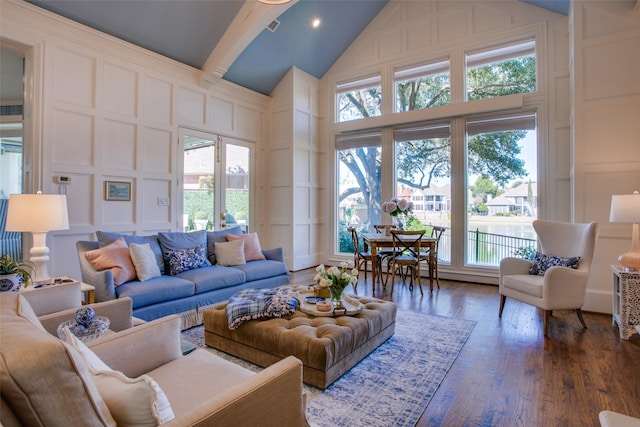 living area with high vaulted ceiling, dark wood-style flooring, and a decorative wall