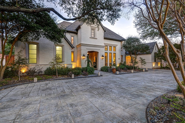 french country style house with driveway and brick siding