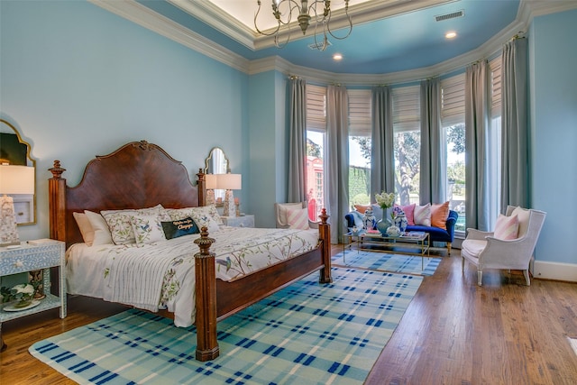 bedroom featuring crown molding, visible vents, an inviting chandelier, wood finished floors, and baseboards