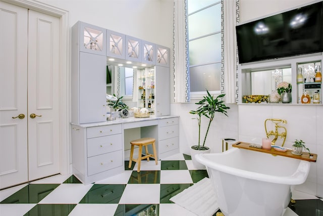 full bathroom with a closet, a freestanding tub, and tile patterned floors