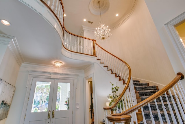 foyer entrance featuring a high ceiling, stairs, crown molding, french doors, and a notable chandelier