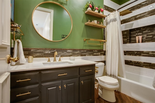 bathroom with toilet, a wainscoted wall, vanity, tile walls, and shower / tub combo with curtain