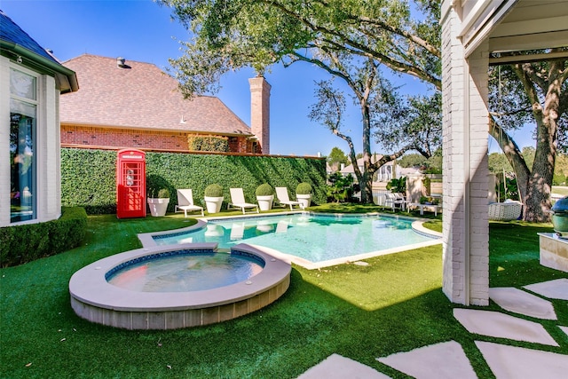 view of pool featuring a lawn and a pool with connected hot tub