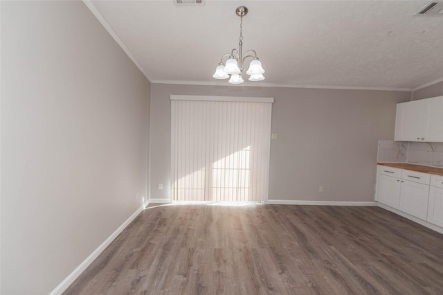 unfurnished dining area featuring ornamental molding, visible vents, and wood finished floors