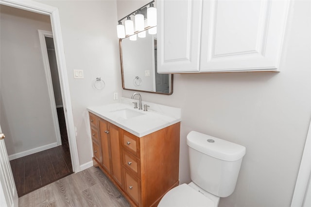 bathroom featuring toilet, baseboards, wood finished floors, and vanity