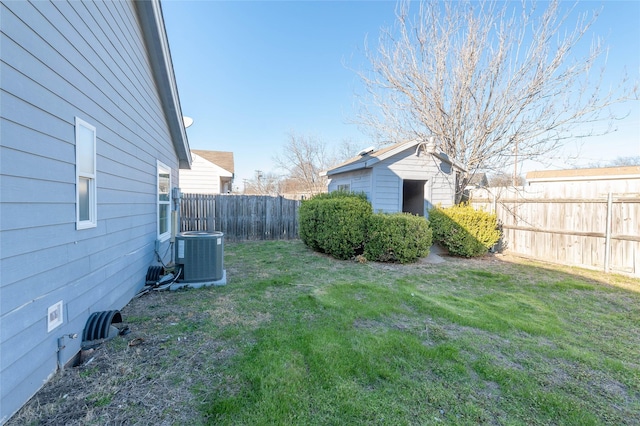 view of yard featuring a fenced backyard, a shed, cooling unit, and an outbuilding