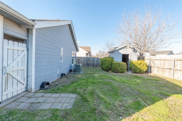 view of yard with central air condition unit, a fenced backyard, an outdoor structure, and a shed