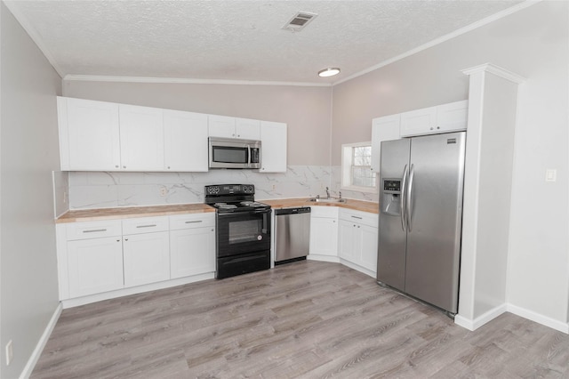 kitchen with white cabinets, light wood-type flooring, wood counters, and stainless steel appliances