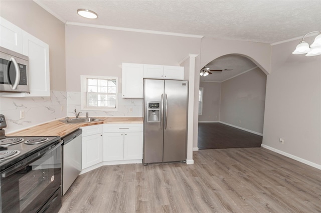 kitchen featuring white cabinetry, stainless steel appliances, and arched walkways