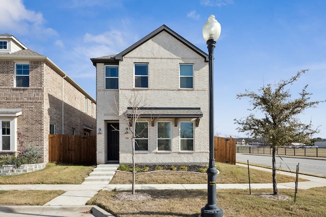 view of front facade featuring brick siding and fence