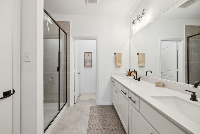 full bath with double vanity, a shower stall, visible vents, and a sink