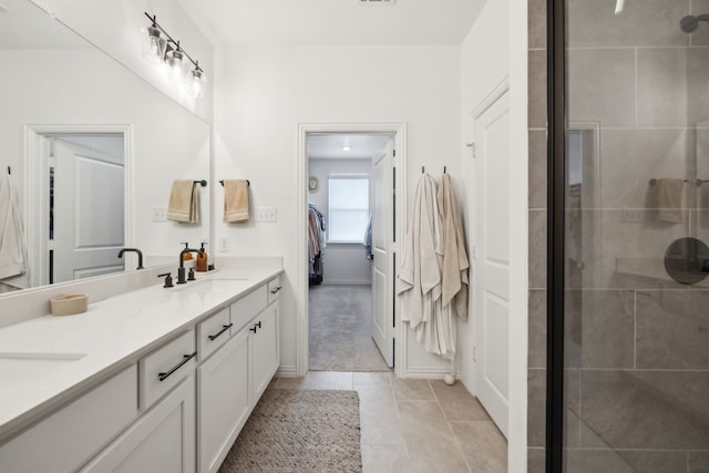 full bath featuring tile patterned floors, tiled shower, a sink, and double vanity