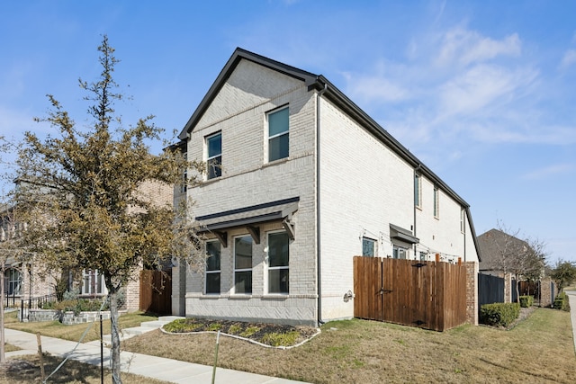 view of side of property with a yard, brick siding, and fence